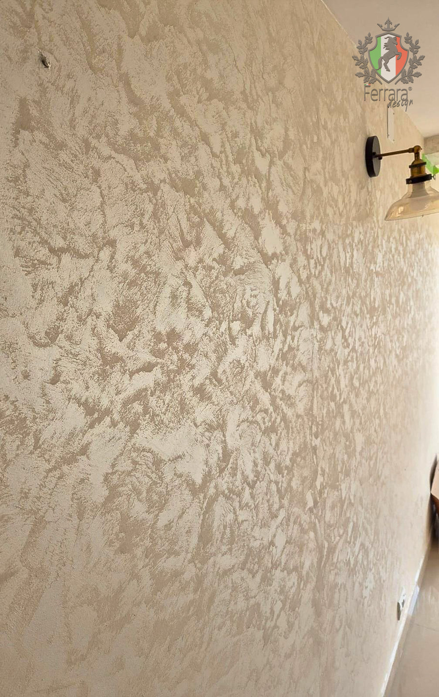 Beige textured wall with a distressed, pebbled pattern, shown on an interior wall next to a wall sconce.
