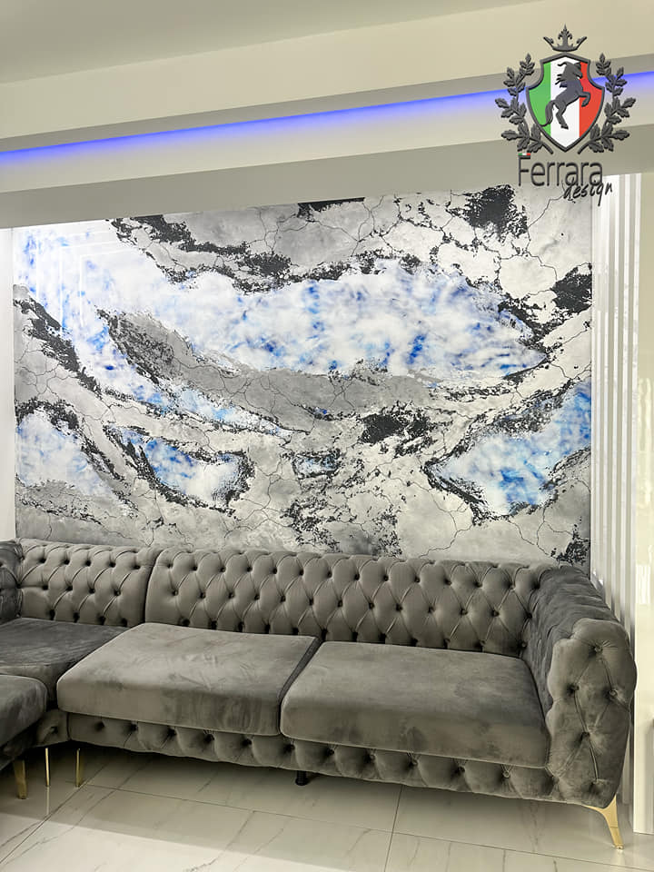 Gray tufted sofa in front of a marble-patterned wall with Ferrara Design logo.