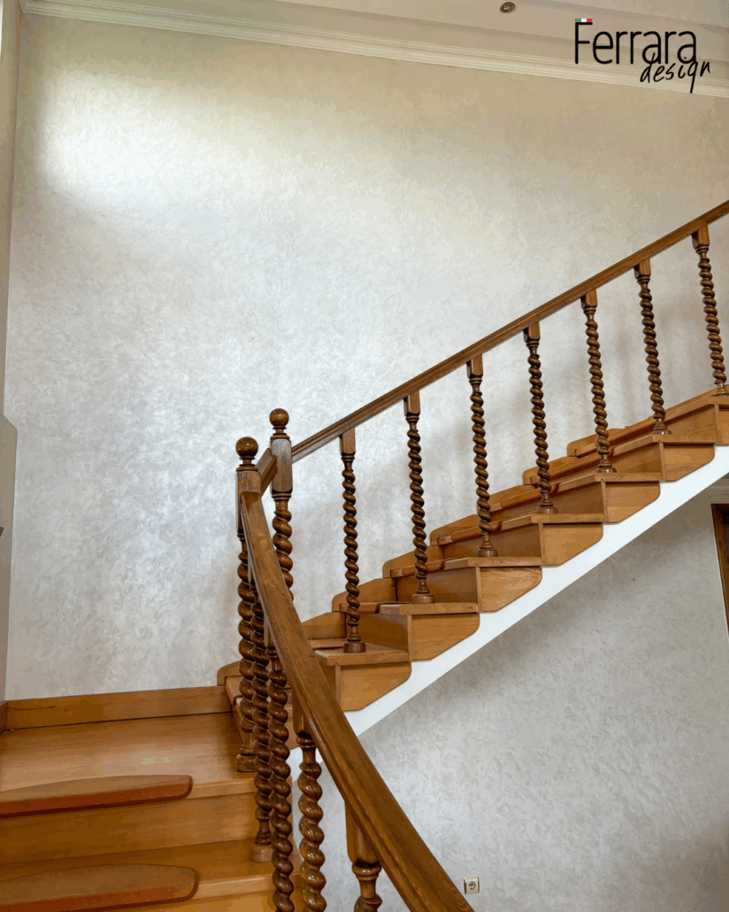 Wooden staircase with spindles against a light wall, featuring 'Ferrara design' branding.