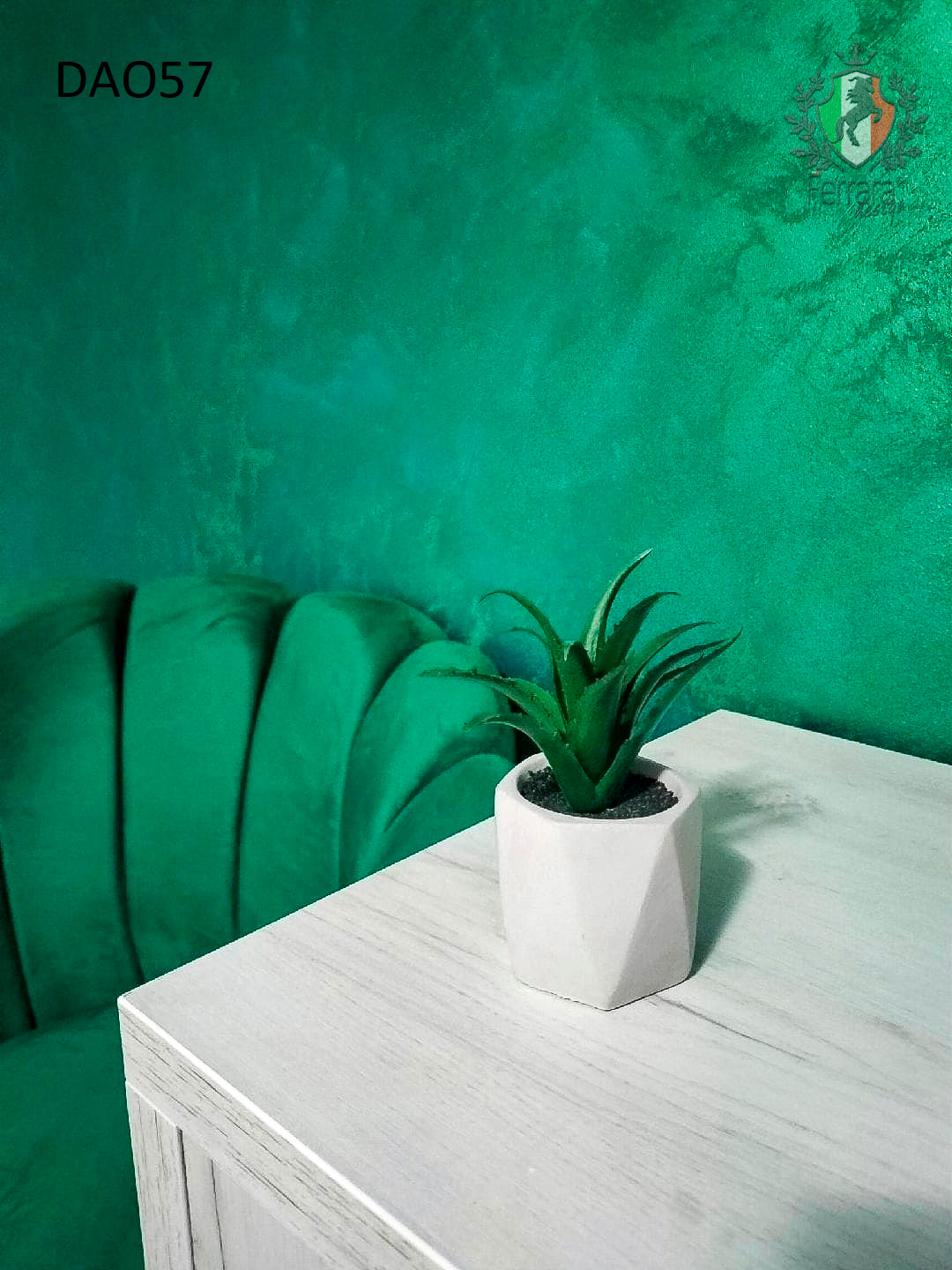 Small potted plant on a white surface with a green textured wall in the background